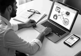 Mann arbeitet am Laptop und Smartphone an seinen Profilen in den Sozialen Medien
